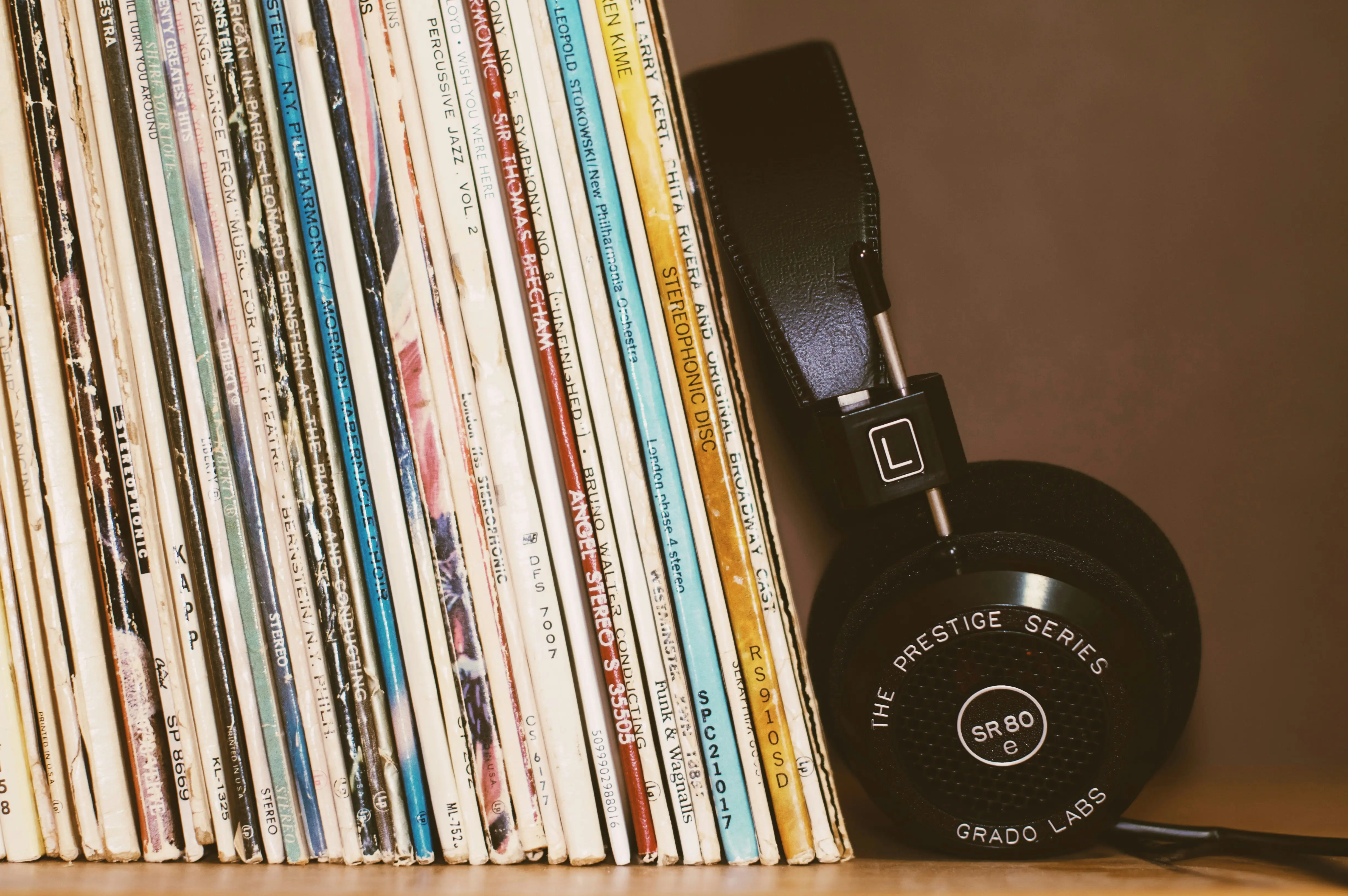 headphones next to a row of used records